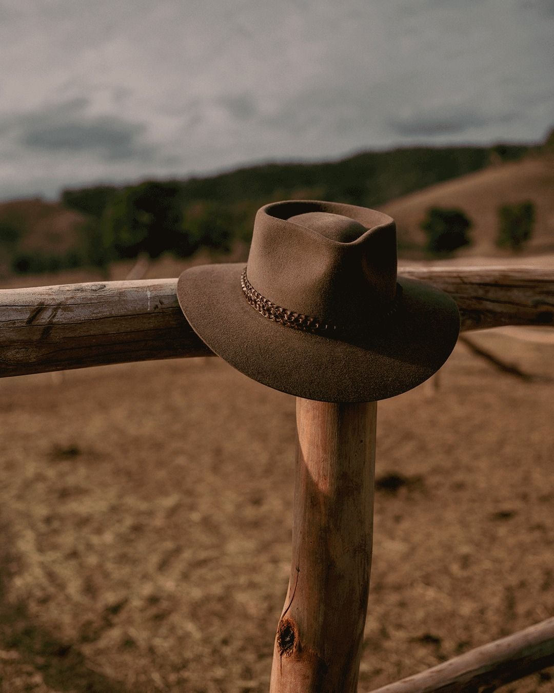 A worn hat resting on a fence rail