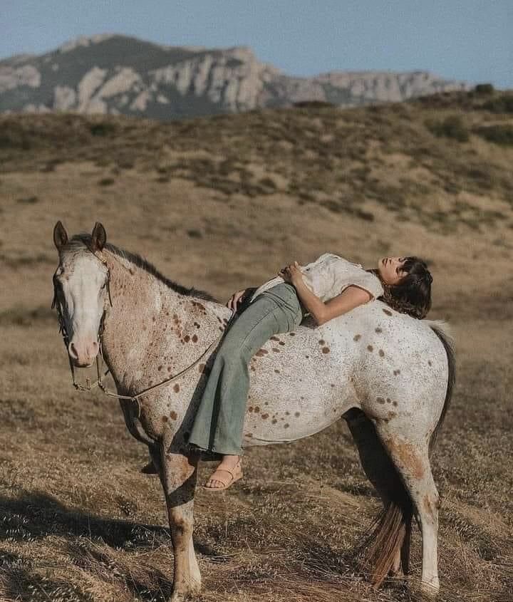 Loes resting against her horse on a hillside